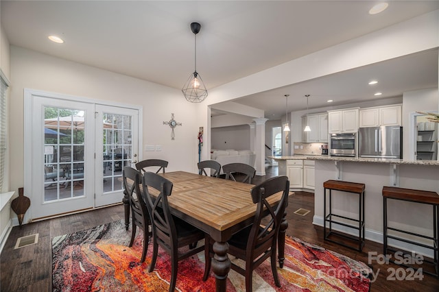 dining space featuring dark wood-type flooring and decorative columns