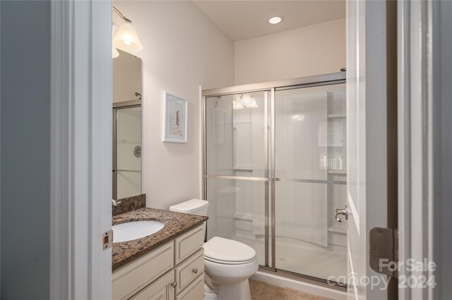 bathroom featuring vanity, toilet, an enclosed shower, and tile patterned floors