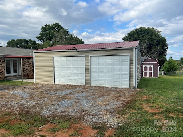 detached garage with a storage unit, french doors, and fence