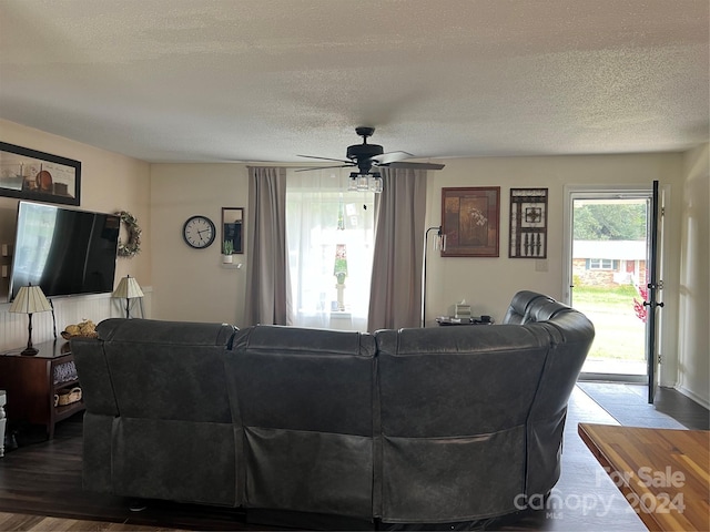 living area featuring dark wood finished floors, ceiling fan, and a textured ceiling