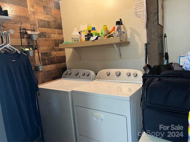 clothes washing area with washing machine and clothes dryer, laundry area, and wood walls