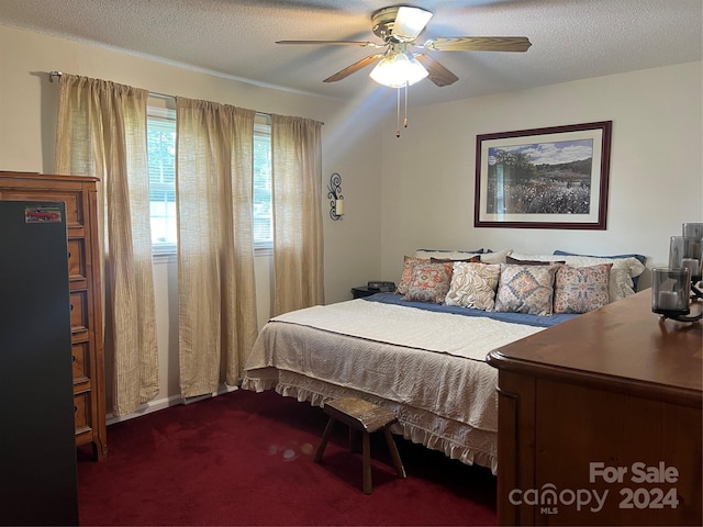 bedroom featuring ceiling fan, dark carpet, and a textured ceiling