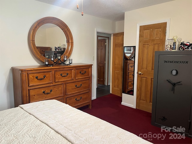 bedroom with dark carpet and a textured ceiling