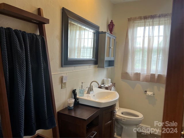 bathroom featuring vanity, toilet, and tile walls