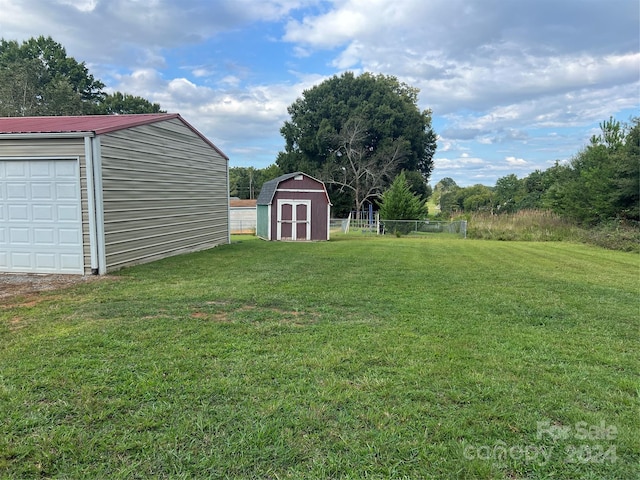 view of yard featuring a garage, an outdoor structure, a shed, and fence