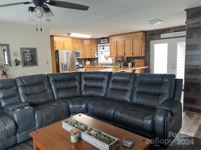 living area with french doors, a textured ceiling, wood finished floors, and a ceiling fan