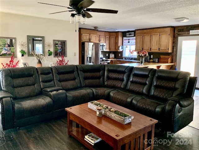 living room featuring a textured ceiling, dark hardwood / wood-style flooring, ceiling fan, and sink