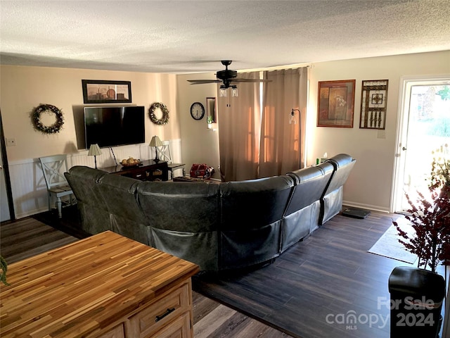 living room with dark wood-type flooring, a ceiling fan, baseboards, and a textured ceiling