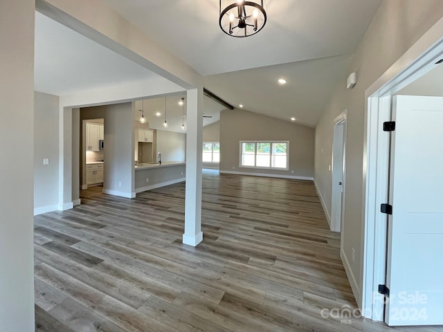 interior space with light wood-type flooring, a notable chandelier, and vaulted ceiling with beams