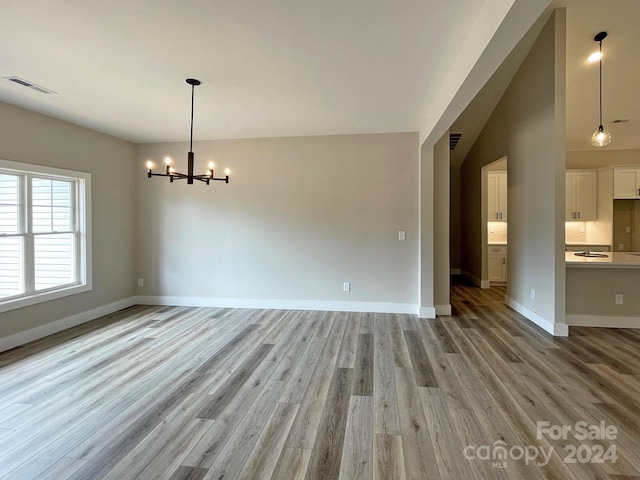 empty room with an inviting chandelier and light hardwood / wood-style floors