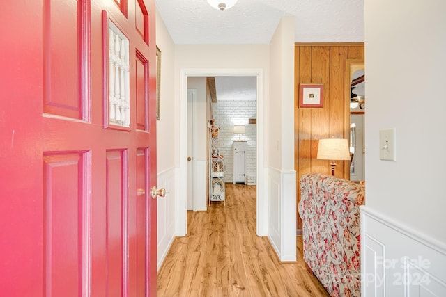 corridor featuring light wood-type flooring and a textured ceiling