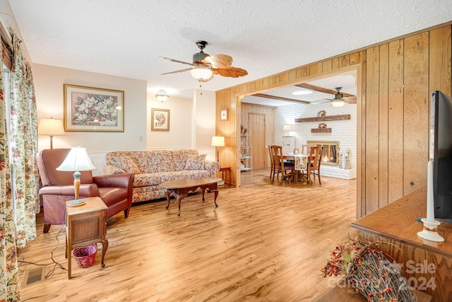 living room with ceiling fan, wood walls, and light hardwood / wood-style floors