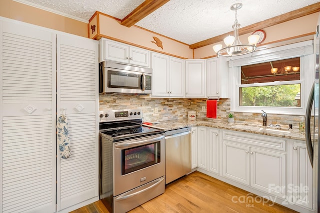 kitchen featuring white cabinets, sink, light hardwood / wood-style flooring, a chandelier, and stainless steel appliances