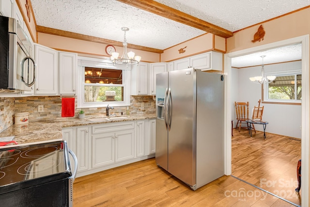 kitchen featuring pendant lighting, white cabinets, sink, appliances with stainless steel finishes, and light hardwood / wood-style floors