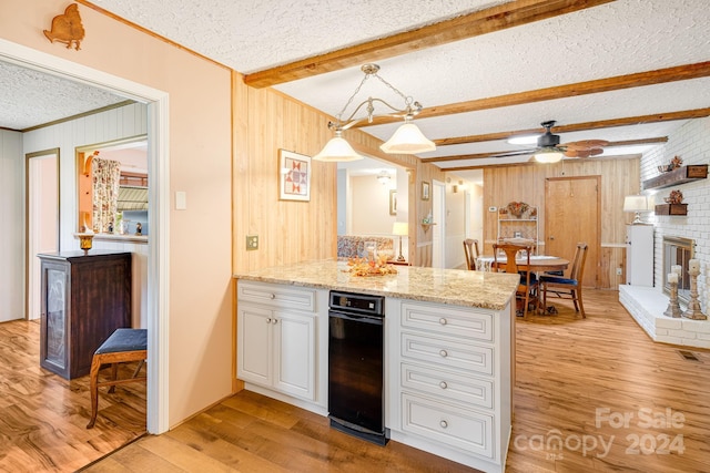 kitchen featuring ceiling fan, hanging light fixtures, a textured ceiling, a fireplace, and light wood-type flooring