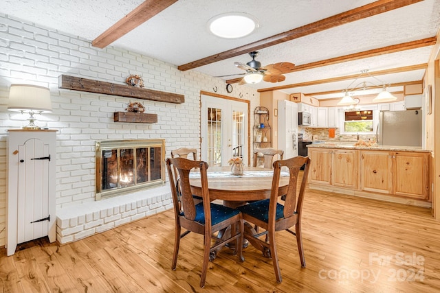 dining space featuring a textured ceiling, light hardwood / wood-style floors, beam ceiling, and a brick fireplace