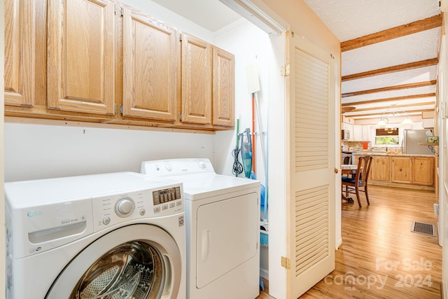 washroom with cabinets, light hardwood / wood-style floors, and washing machine and clothes dryer