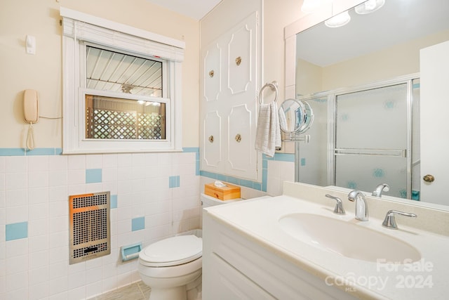 bathroom featuring tile walls, heating unit, vanity, walk in shower, and toilet