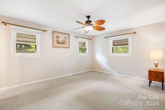 carpeted empty room with ceiling fan and a textured ceiling