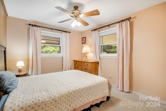 bedroom with a textured ceiling, light carpet, and ceiling fan