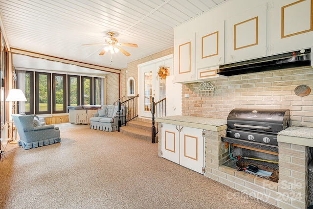 living room with ceiling fan, a brick fireplace, and brick wall