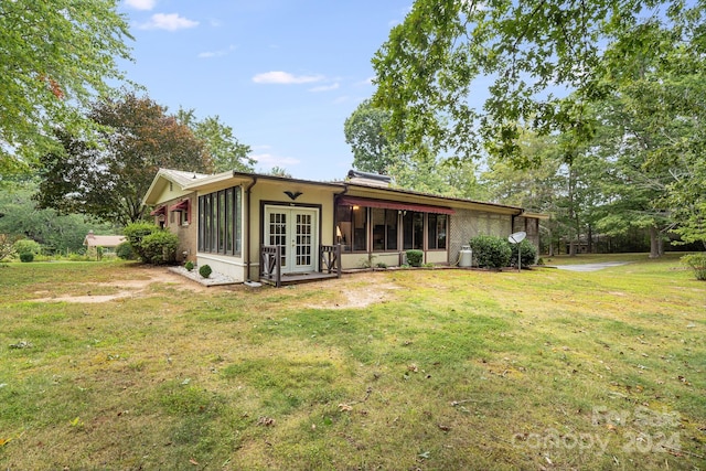 back of property with a lawn and french doors