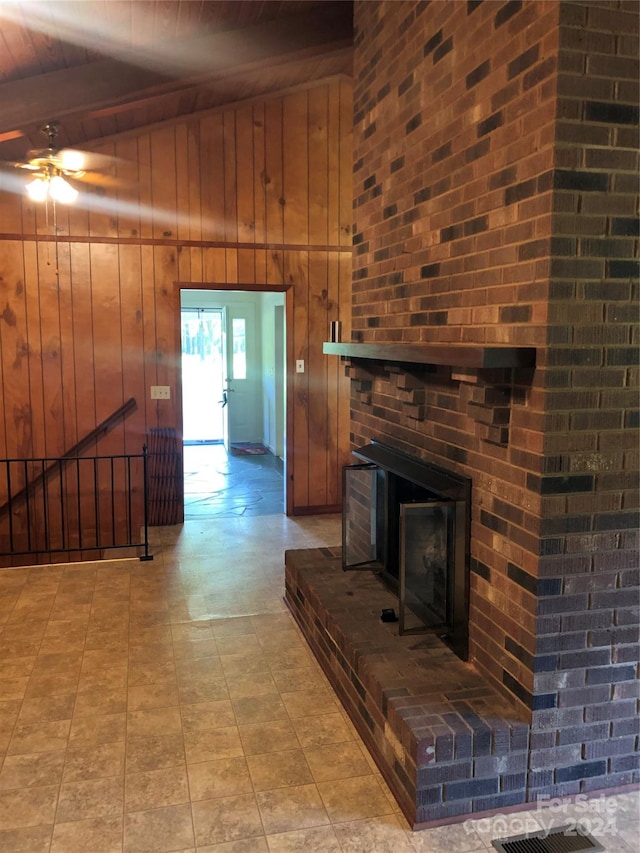 living room with ceiling fan, vaulted ceiling with beams, a brick fireplace, wooden walls, and wooden ceiling