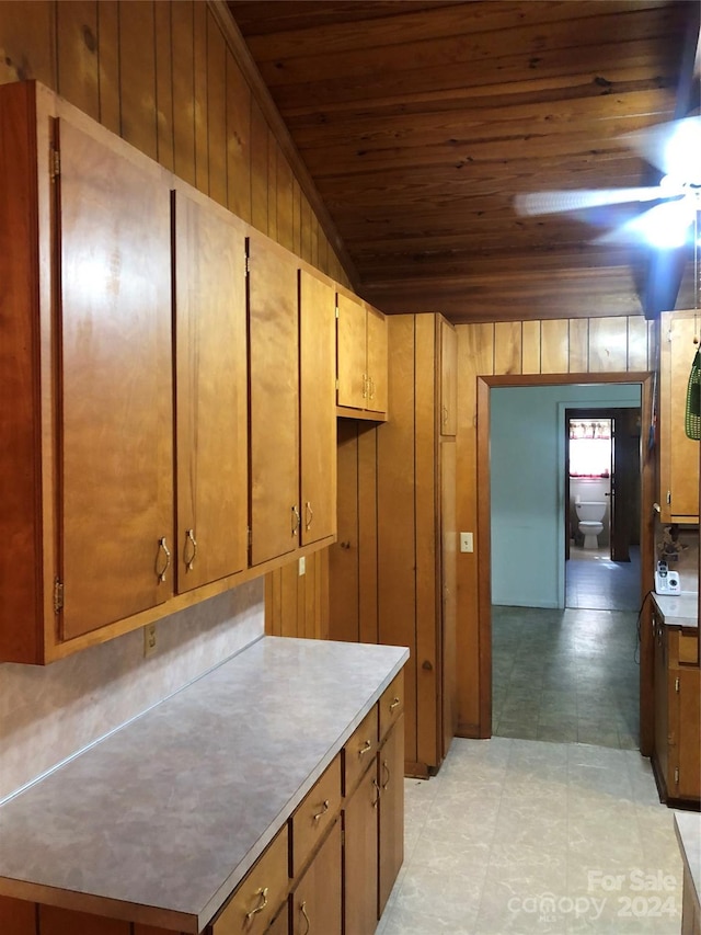 kitchen featuring wood ceiling, wood walls, lofted ceiling, and ceiling fan