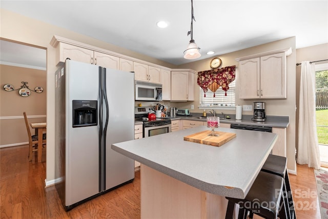 kitchen featuring light hardwood / wood-style flooring, a center island, stainless steel appliances, sink, and hanging light fixtures