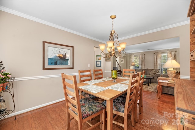 dining room featuring crown molding, hardwood / wood-style floors, and an inviting chandelier