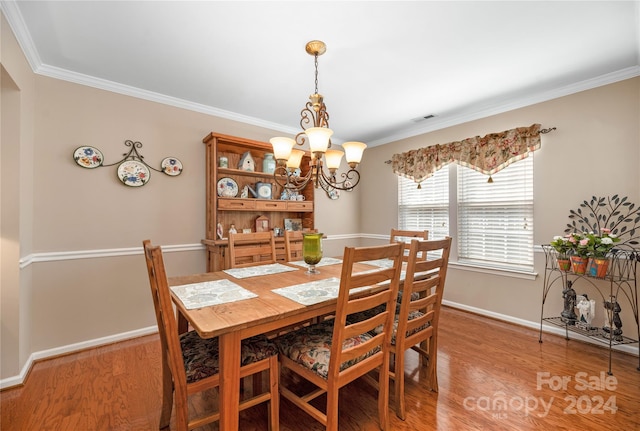 dining space featuring crown molding, light hardwood / wood-style flooring, and a notable chandelier