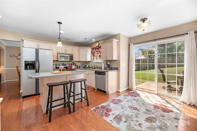 kitchen featuring a kitchen island, decorative light fixtures, a kitchen bar, stainless steel appliances, and light wood-type flooring