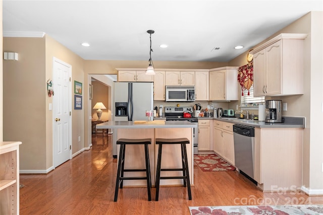 kitchen featuring hanging light fixtures, a center island, stainless steel appliances, sink, and light wood-type flooring