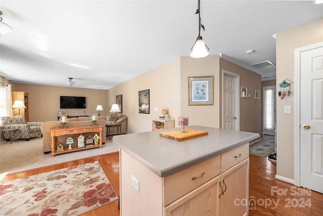 kitchen with light hardwood / wood-style flooring, light brown cabinetry, ornamental molding, and a center island