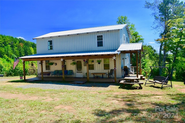 rear view of house featuring a lawn and a porch