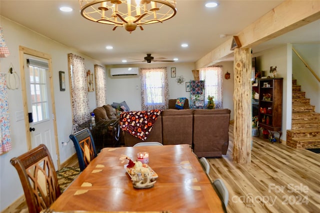 dining area with ceiling fan with notable chandelier, a wall unit AC, and hardwood / wood-style flooring