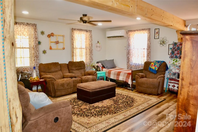 living room featuring light wood-type flooring, plenty of natural light, an AC wall unit, and ceiling fan