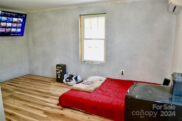 bedroom featuring an AC wall unit and light hardwood / wood-style floors