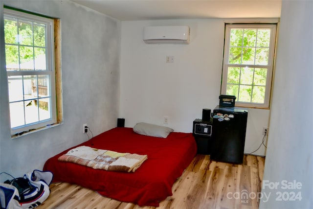 bedroom with an AC wall unit and light hardwood / wood-style flooring