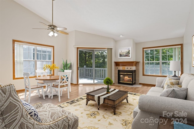 living room with plenty of natural light, lofted ceiling, ceiling fan, and a tiled fireplace