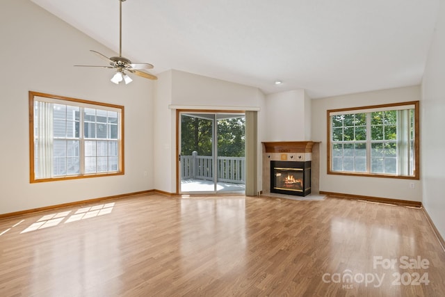 unfurnished living room featuring light hardwood / wood-style flooring, a tiled fireplace, ceiling fan, and vaulted ceiling