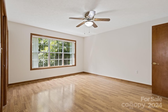 spare room featuring light wood-type flooring, ceiling fan, and a textured ceiling