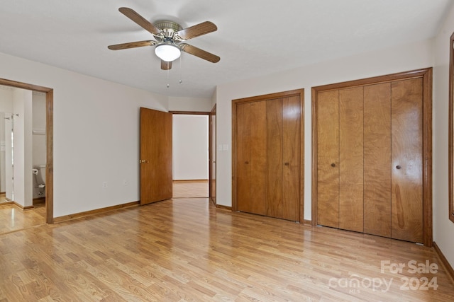 unfurnished bedroom featuring connected bathroom, light hardwood / wood-style floors, two closets, and ceiling fan