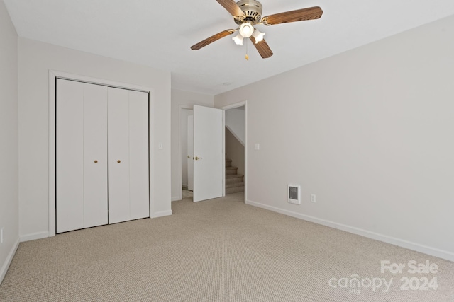 unfurnished bedroom with ceiling fan, a closet, and light carpet