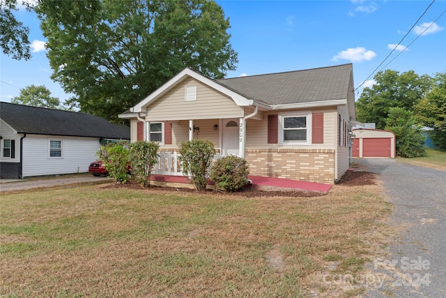 view of front of property with an outbuilding, a garage, covered porch, and a front yard