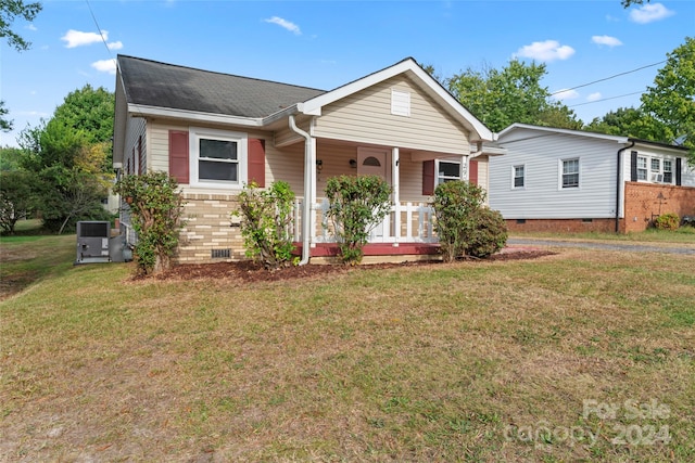 view of front of house with covered porch, central AC unit, and a front yard