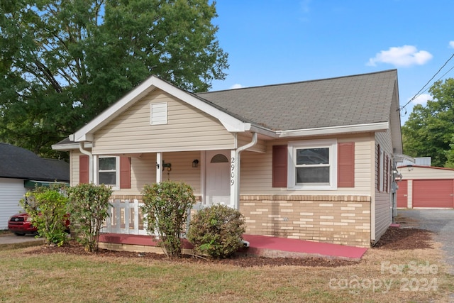 view of front of home with a front yard, a garage, an outdoor structure, and a porch