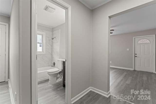 full bathroom with wood-type flooring, ceiling fan, tiled shower / bath, vanity, and toilet