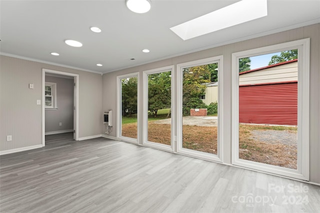 spare room with light wood-type flooring, ornamental molding, heating unit, and a skylight