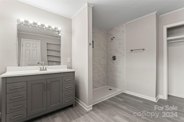 bathroom featuring wood-type flooring, vanity, and tiled shower